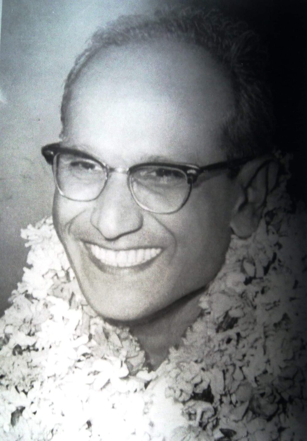 Portrait of Batukeshwar Dutt in later life, wearing spectacles and a flower garland.